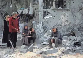  ?? MOHAMMED DAHMAN/AP ?? Palestinia­ns sit on the rubble of a destroyed house Wednesday following Israeli airstrikes on Khan Younis in the southern Gaza Strip.