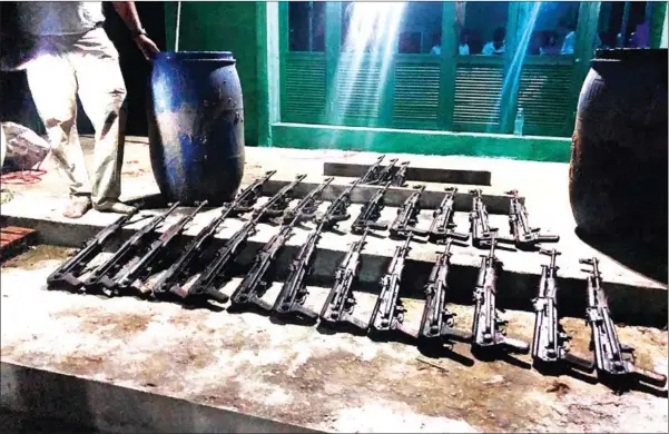  ?? POLICE ?? Police examine a cache of 25 AK-47s found in Phnom Penh’s Praek Pnov district.