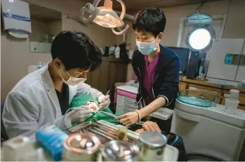  ?? CHANG W. LEE/THE NEW YORK TIMES ?? Lee Gang-min, a dentist, treats Park Meng-sim, 67, on July 20, 2022, aboard the Chungnam 501, a government-run hospital ship that brings free medical services to the residents of remote islands, in Hodo, South Korea.