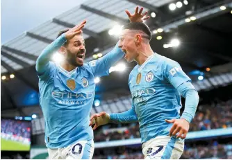  ?? EPA-Yonhap ?? Manchester City’s Phil Foden, right, celebrates with teammate Bernado Silva after scoring against Manchester United during an English Premier League football at the Etihad Stadium in Manchester, Sunday.