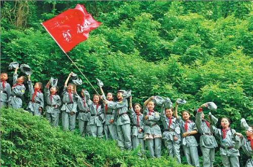  ?? QIU HAIYING / XINHUA ?? Wearing Red Army uniforms, students from a primary school in Huaying city, Sichuan province, experience the Red Army’s Long March by climbing a steep hill.