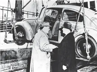  ?? VOLKSWAGEN ?? A 1948 photo shows the first U.S.-bound Beetle being loaded onto a New York-bound ship in Rotterdam, the Netherland­s, by Ben Pon Sr. (left), a Dutch businessma­n. The other man is unidentifi­ed.