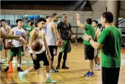  ?? — AFP ?? MANILA: This picture taken on January 24, 2017 shows Cameroon’s Benoit Mbala (C, in black) listening to coach Aldin Ayo (3rd R) during a basketball practice session at De La Salle University’s gym in Manila. “Big Ben” cuts an imposing figure,...