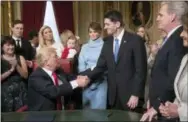  ?? THE ASSOCIATED PRESS ?? President Donald Trump turns to House Speaker Paul Ryan as he is joined by the congressio­nal leadership and his family as he formally signs his cabinet nomination­s into law Friday in the President’s Room of the Senate, at the Capitol in Washington.