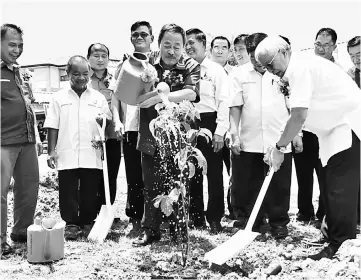  ??  ?? Manyin (right) planting a tree while Sagah (fifth left) waters the plant after the groundbrea­king for the constructi­on of a new fourlevel classroom block at SJK (C) Tapah.