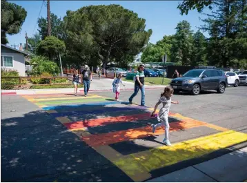  ?? LEZLIE STERLING — THE SACRAMENTO BEE ?? Parents and students cross the street while walking in a rainbow-colored crosswalk across from Birch Lane Elementary School in Davis on May 25, 2023. The crosswalk was painted that way for LGBTQ Pride Month.