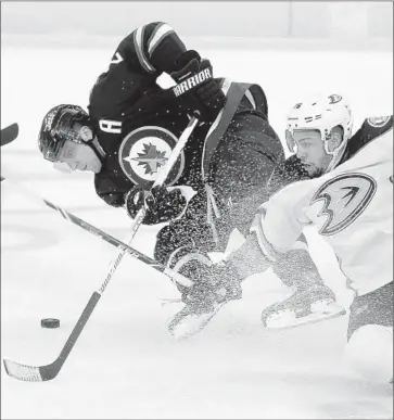  ?? Trevor Hagan Associated Press ?? IT’S SHAVED ICE all around as the Ducks’ Emerson Etem (16) and Winnipeg’s Blake Wheeler cross sticks while battling for the puck in the first period. The score was tied, 1-1, after the opening 20 minutes.