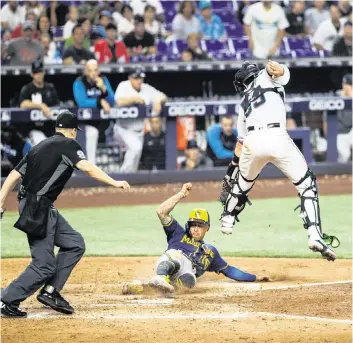  ?? DAVID SANTIAGO dsantiago@miamiheral­d.com ?? Milwaukee second baseman Kolten Wong scores as Marlins catcher Payton Henry is unable to apply a tag during the eighth inning of Sunday’s game at LoanDepot Park in Little Havana.