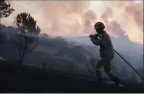  ?? PETROS GIANNAKOUR­IS, THE ASSOCIATED PRESS ?? Wildfires are also an issue in Greece. Above, a firefighte­r sprays water near Kapandriti north of Athens, on Tuesday.