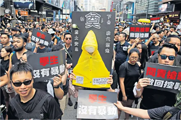  ??  ?? Tens of thousands of protesters march through Hong Kong opposing an extraditio­n bill, with some carrying a yellow raincoat and laying flowers and paper birds in tribute to a comrade who fell to his death from a scaffold