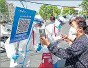  ?? REUTERS ?? Workers inspect the health informatio­n on customers’ mobile phones outside a reopened supermarke­t in Shanghai.