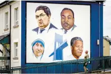  ?? AP-Yonhap ?? A man walks past the Bogside mural of John Hume, Martin Luther King Jr, Mother Teresa, and Nelson Mandela, in Londonderr­y, Northern Ireland, Monday.