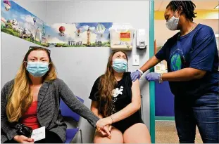  ?? PHOTOS BY HYOSUB SHIN/HYOSUB.SHIN@AJC.COM ?? Lucy Saravia, 13, receives a first dose of the Pfizer vaccine Wednesday from Pheona Mack (right) as Saravia’s mother Robin Mead steadies her at Dekalb Pediatric Center. More than a thousand patients took advantage of the chance to get their first shot at the clinic that’s partnering with the local school system to vaccinate students.