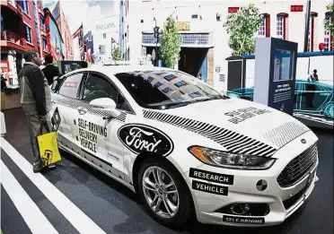  ?? — AP ?? Expansion plan: An attendee looks at Ford’s self-driving delivery vehicle at CES Internatio­nal in Las Vegas. Ford will expand delivery partners beyond Dominos Pizza and San Francisco-based Postmates