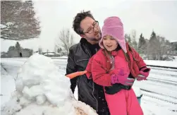  ?? AP ?? Jonathan Bugg, of Felida, and his daughter, Riley, 4, look over their snowman in Vancouver, Wash., on Tuesday. One to 2 inches of snow fell on the city.