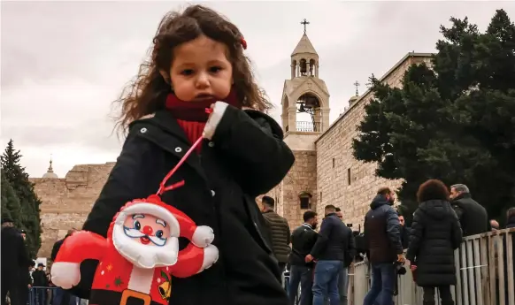  ?? AFP ?? A girl with an inflatable Father Christmas at the Manger Square outside the Church of the Nativity in Bethlehem in the occupied West Bank yesterday