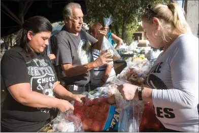  ?? RECORDER PHOTOS BY CHIEKO HARA ?? Volunteers pack food items to prepare more than 250 food baskets Tuesday, Nov. 20 at the annual Thanksgivi­ng food giveaway at El Granito Foundation in Portervill­e.