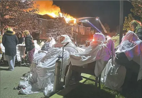  ?? Pete Bannon/Daily Local News via AP ?? Residents of Barclay Friends Senior Living Community wait to be taken to ambulances Thursday night as the senior care facility burned in West Chester, Pa.