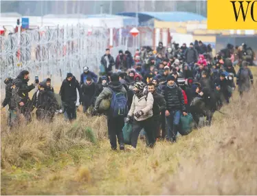  ?? LEONID SHCHEGLOV / BELTA / AFP VIA GETTY IMAGES ?? Migrants move along the Belarusian-polish border Friday toward a camp to join others hoping to enter Poland.