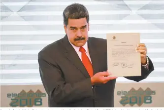  ?? AFP-Yonhap ?? Venezuelan President Nicolas Maduro shows the document issued by the National Electoral Council (CNE) that proclaims him as re-elected President for the term 2019-2025, at the CNE headquarte­rs in the in Caracas, Tuesday.