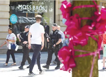  ?? / AP FOTO ?? RIBBONS FOR PEACE. Armed police patrol past tribute pink ribbons on a tree in central Manchester, England. More than 20 people were killed in an explosion following a Ariana Grande concert at the Manchester Arena late Monday evening. A severe threat...