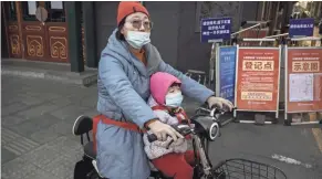  ?? KEVIN FRAYER/GETTY IMAGES ?? A Chinese woman and her daughter wear protective masks aboard a scooter Wednesday in Beijing.