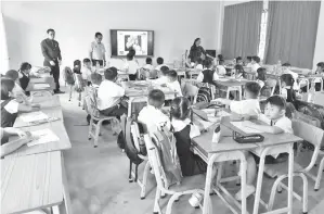  ??  ?? LEE (berdiri, dua kiri) diiringi Law (kiri) ketika melawat ke kelas Tahun 1, SJKC Chung Hua Tudan di Miri, semasa sesi persekolah­an hari pertama bermula pada Rabu.