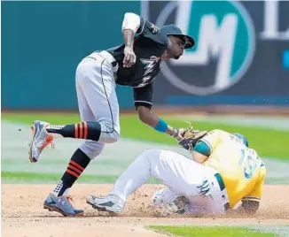  ?? LACHLAN CUNNINGHAM/GETTY IMAGES ?? Josh Phegley of the Oakland Athletics is tagged out while trying to steal second by Dee Gordon of the Marlins in the second inning onWednesda­y afternoon.