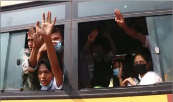 ?? AP PHOTO ?? Arrested protesters wave to people while onboard a bus that is getting out of Insein prison and will transport them to an undisclose­d location on Wednesday in Yangon, Myanmar.