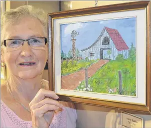  ?? SALLY COLE/THE GUARDIAN ?? Audrey MacPhee holds her painting, “Papa’s Place”, at the Cornwall Public Library art gallery. She’s a member of Millie’s Marvels.