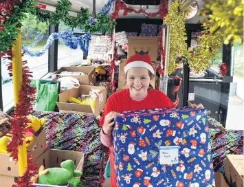  ?? PHOTO: PETER MCINTOSH ?? Christmas spirit . . . Wakari School pupil Isabelle Stanton brings a big gift on to the bus during a ‘‘Stock the Bus’’ initiative in Dunedin yesterday.