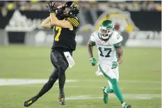  ??  ?? The Tiger-Cats’ Luke Tasker makes a catch as the Roughrider­s’ Crezdon Butler closes in on him Friday night at Tim Hortons Field in Hamilton.