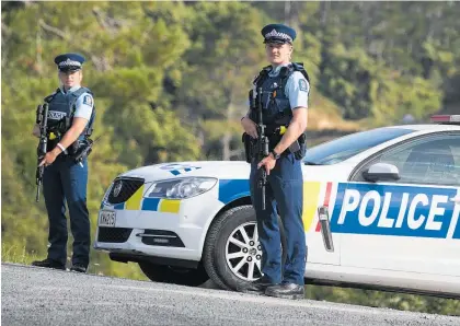  ?? Photo / Alan Gibson ?? Armed police at a cordon on a street west of Tauranga yesterday after two men died on Tuesday.