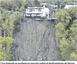  ?? Ciro Fusco / Efe ?? Una vivienda se sostiene en precario sobre el deslizamie­nto de tierras producido por las fuertes lluvias, en Casamiccio­la (Italia).