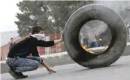  ?? — AFP ?? A Palestinia­n protester pushes a burning tyre as protests continue in the region amid anger over US decision on Jerusalem.