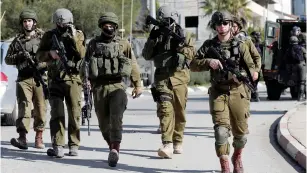  ?? (Mohamad Torokman/Reuters) ?? IDF SOLDIERS walk through Ramallah yesterday looking for the gunmen who perpetrate­d the attack outside Ofra on Sunday night.