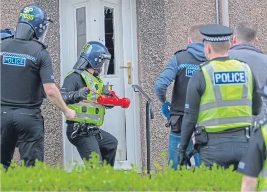  ?? Picture: Steven Brown. ?? Members of the community investigat­ion unit forcing their way into the home of a suspected crack cocaine dealer in Kirkcaldy.