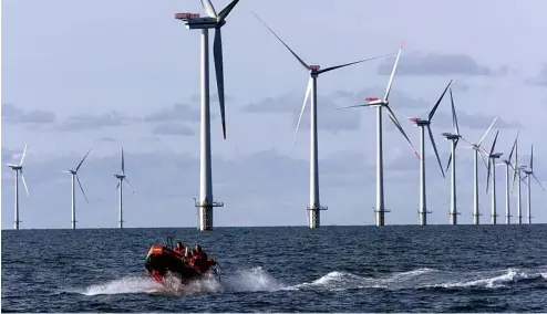  ?? ?? Un canot pneumatiqu­e passe devant des turbines en mer du Nord, à 14 kilomètres à l'ouest du petit village de Blavand, près d'Esbjerg, au Danemark.
