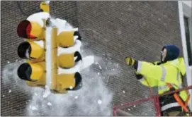  ?? ASSOCIATED PRESS ?? City of Erie traffic engineerin­g employee Chuck Carnes Jr. uses compressed air to clear snow from a traffic signal in Erie, Pa., on Dec. 27. Carnes was part of a two-man crew clearing signals after a recordsett­ing snowfall.