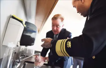  ?? Jessica Hill / Associated Press ?? U. S. Surgeon General Vice Admiral Jerome M. Adams demonstrat­es the proper way to wash hands with Gov. Ned Lamont during a visit to the Connecticu­t State Public Health Laboratory on March 2, 2020, in Rocky Hill.