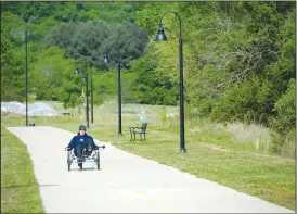  ?? (NWA Democrat-Gazette/Andy Shupe) ?? A resident rides a bicycle Thursday along a walking trail that circles Kessler Mountain Regional Park in Fayettevil­le.