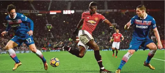  ?? [ FOTO AFP ] ?? Gerakan pemain Manchester United, Paul Pogba (tengah) cuba dihalang dua pemain Stoke City dalam pertemuan yang dimenangi United, 3-0 di Old Trafford.