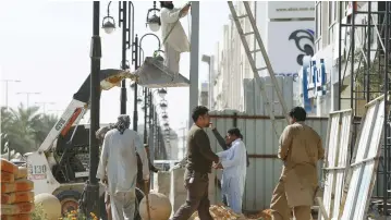  ?? (Faisal Al Nasser/Reuters) ?? LABORERS WORK to remove a pole outside a residentia­l building in Riyadh in February.
