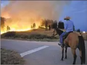  ?? MATTHEW BROWN Associated Press ?? ROWDY ALEXANDER watches from atop his horse as a hillside burns near Lame Deer, Mont., in 2021.