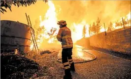  ?? PAULO NOVAIS/EPA ?? A firefighte­r battles Sunday in Portugal, where a lightning strike may have sparked the fire.