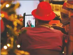  ??  ?? Luigi Zanini, flanked by Madaschi, talks via video call with Ilaria Sacco, a donor unrelated to him, who bought and sent him a Christmas present through an organizati­on dubbed “Santa’s Grandchild­ren.”