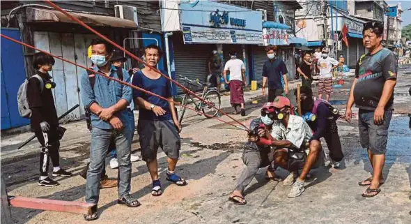  ?? AFP PIC ?? Protesters testing out a large slingshot weapon in Yangon yesterday, as security forces continued a crackdown on demonstrat­ions against the coup.