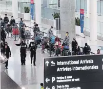  ?? RICHARD LAUTENS TORONTO STAR ?? Passengers who arrived in Toronto on a flight from Delhi, India, wait in line to board buses to quarantine hotels. The hotel stays are among measures to limit the spread of COVID-19.