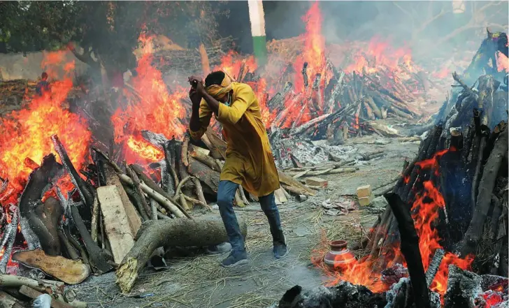  ?? EFE ?? Un hombre huye del fuego que desprenden las piras funerarias improvisad­as que inundan las calles de Nueva Delhi