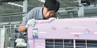  ?? XINHUA ?? A worker inspects an air conditione­r at the production line of Haier Group in Qingdao, Shandong province.